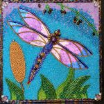 Glass bead mosaic dragonfly with luminous pink wings flying above green leaves and golden cattails on a bright blue background.