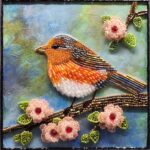 Glass bead mosaic of a colorful songbird perched on a flowering branch